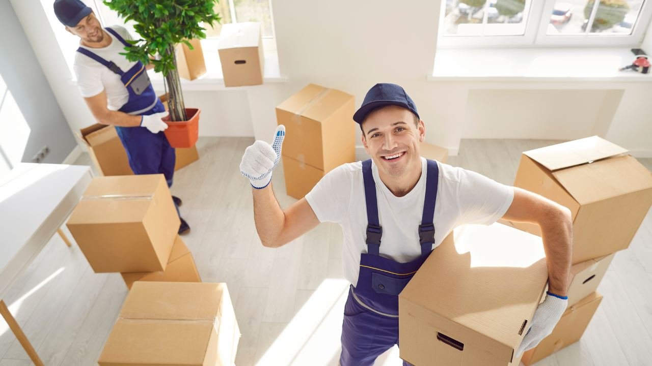 Friendly movers surrounded by boxes and furniture helping with moving a 3-bedroom house in Ontario- Burly Boyz Moving