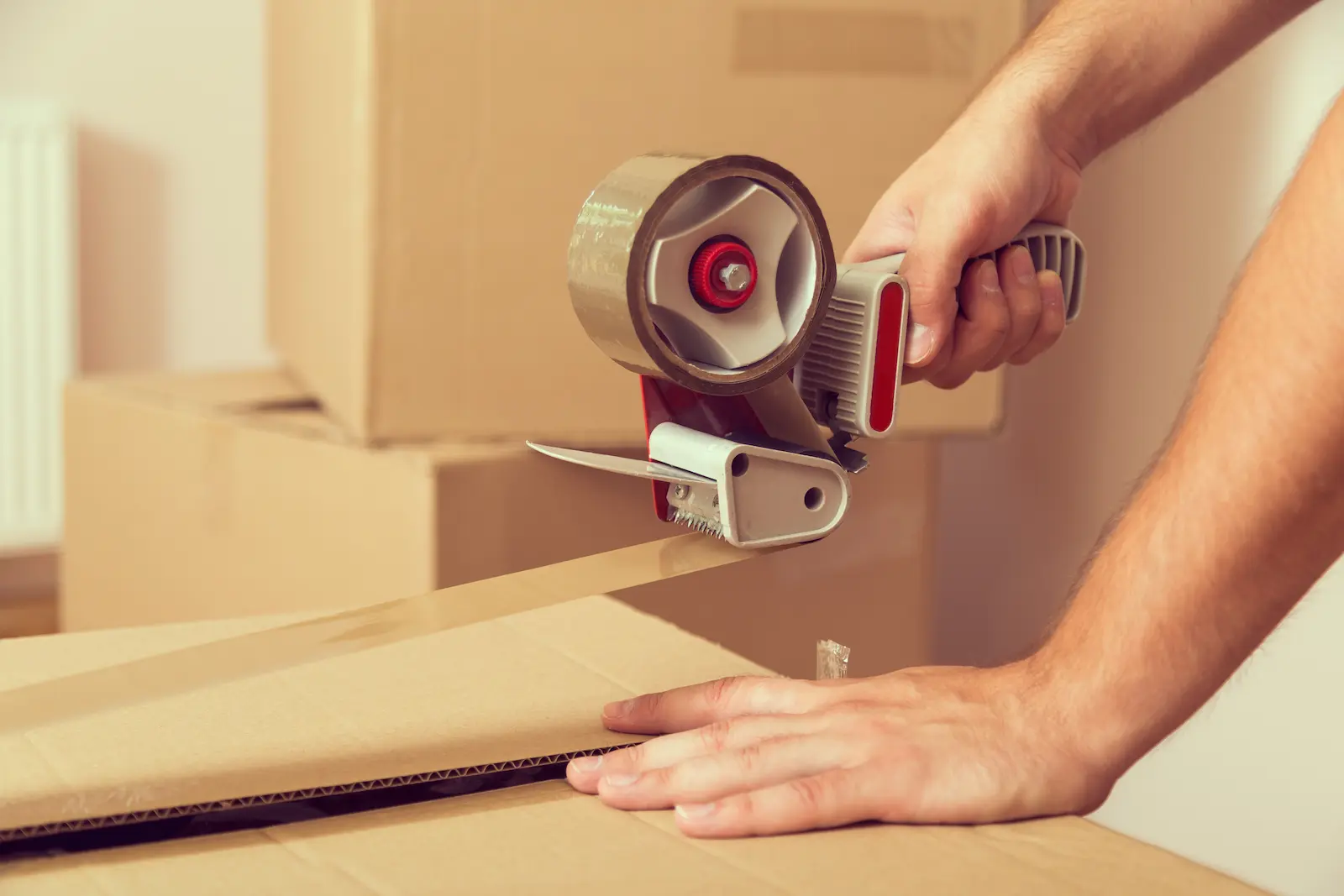 Close-up of a Burly Boy part of the best moving company in Vancouver sealing a cardboard box with packing tape.